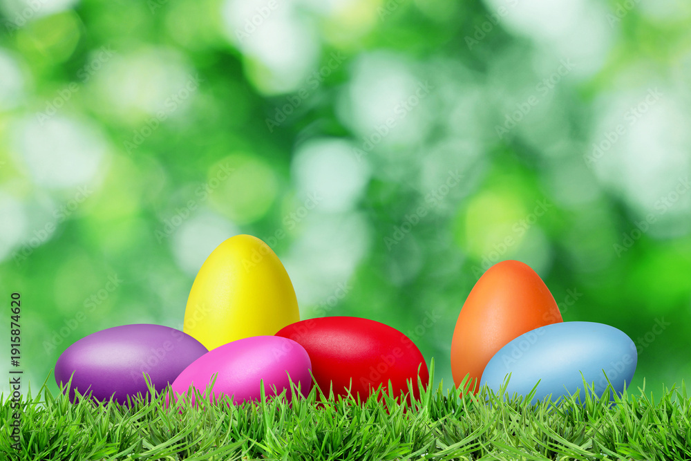 Fototapeta premium Easter eggs in green grass against blurred background