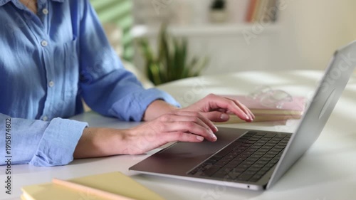 Woman working on laptop at white table indoors, closeup