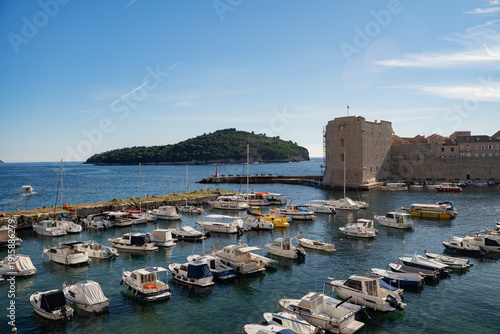 Traditional boats anchored near the historic stone walls of Dubrovnik Old Town, scenic Mediterranean coastline and ancient fortress in Croatia, sunny day