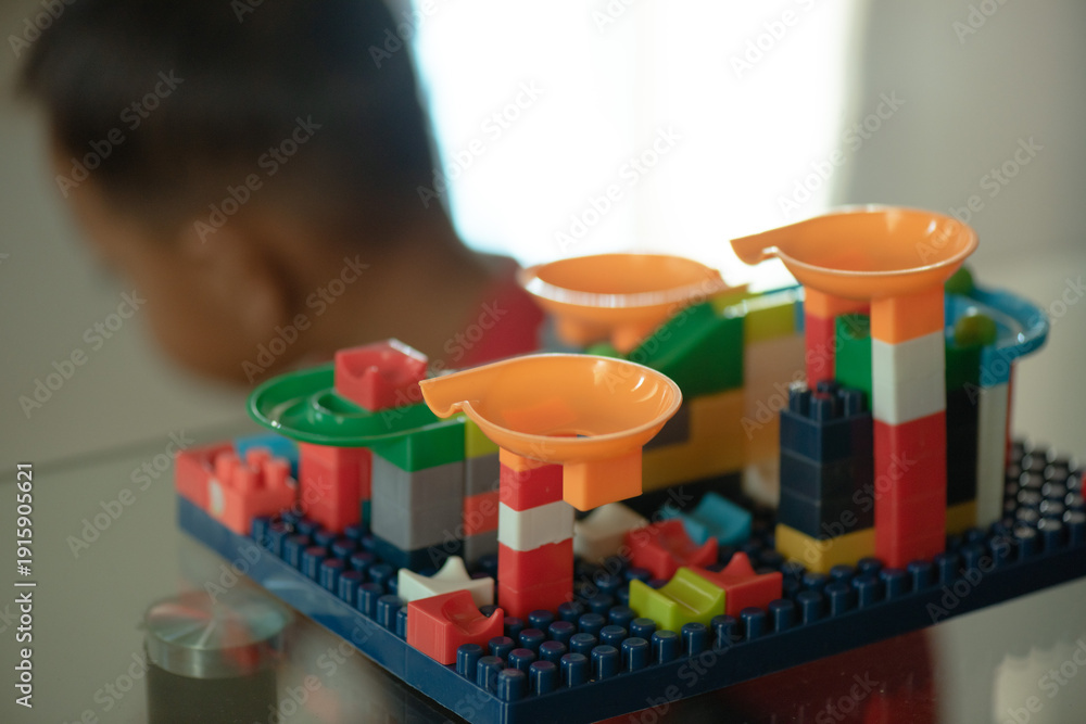 Fototapeta premium Child admires vibrant marble run creative play, education, childhood development, toy store marketing, childcare blogs, parenting websites.