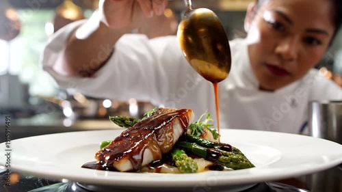 Culinary Craftsmanship: A chef delicately drizzles a rich sauce over a beautifully plated dish, showcasing the art of gastronomy and fine dining excellence.