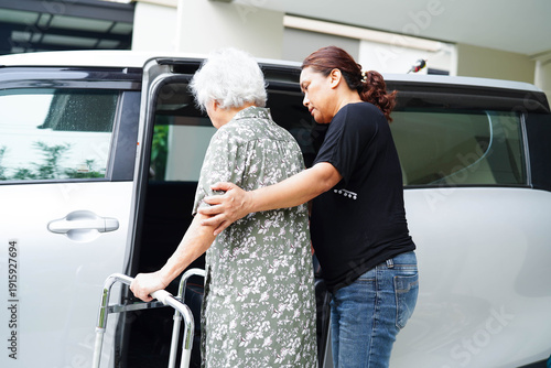 Caregiver help Asian elderly woman disability patient get in her car.