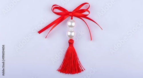 Red ribbon bow with white pearls and tassel on light purple background