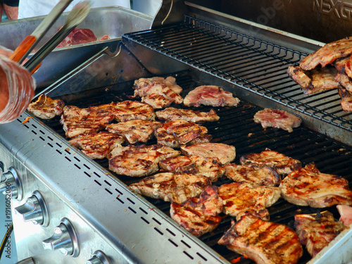 Photos Juicy pork chops searing beautifully on a large outdoor stainless steel barbecue