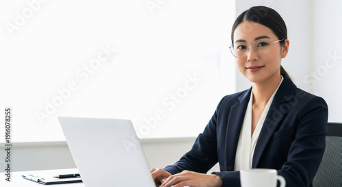 モダンなオフィスでノートパソコンを使う自信に満ちた若いビジネスウーマン。アジア人、日本人