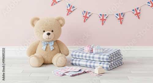 A light-brown teddy bear sits beside a stack of blue and white checkered fabric, a pink toy, and scattered baby clothes against a pink wall with a Union Jack bunting.