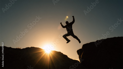 Silhouette Of Brave Man Jumping Across Cliff At Sunset Symbolizing Risk Freedom And Success