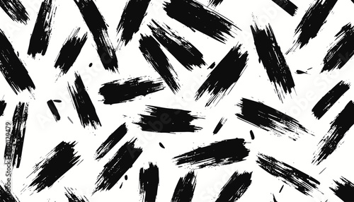 Randomly scattered black brush strokes on a clean surface viewed from directly above creating a dynamic abstract pattern