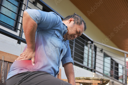 Принти на полотні Middle aged Asian man suffering from chronic back pain or office syndrome while sitting