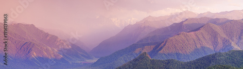 Dramatic sunset in the mountains, stormy sky, forest and peaks in the evening light, panoramic view