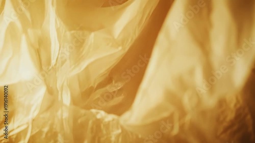 Crumpled golden plastic offers an abstract texture, reflecting warm light and forming intricate creases across the material, ideal for creative backgrounds and design elements