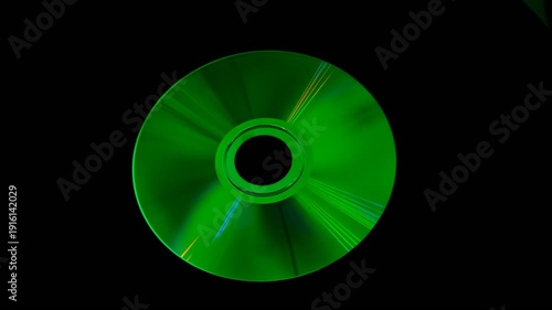 A shiny compact disc reflecting rainbow colors on dark background