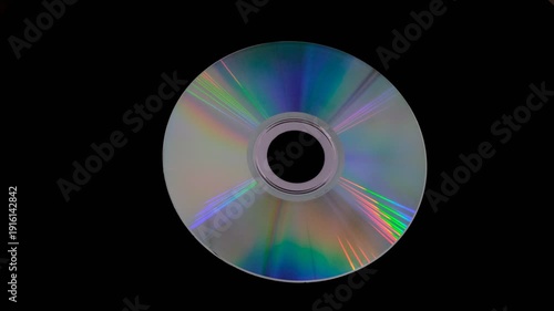 A shiny compact disc reflecting rainbow colors on dark background