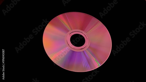A shiny compact disc reflecting rainbow colors on dark background