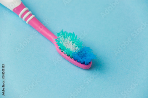 Concept of proper teeth brushing and oral care. Old used toothbrush close-up on a blue background