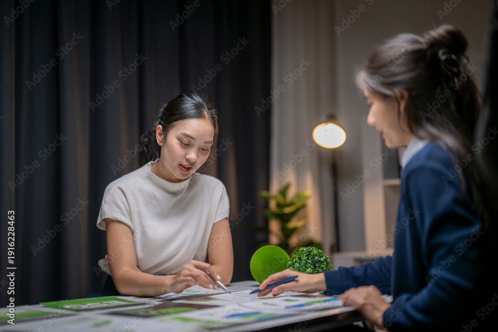 Fototapeta premium Businesswomen collaborating on sustainable project planning late night