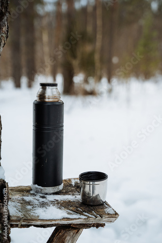 Winter Outdoor Stop. Resting During Snowy Adventure. Cozy Pause Amid Winter Forest During Mountain Hike. Relaxing Moment Outdoors With Hot Beverage On Rustic Wooden Shelf In Snowfall