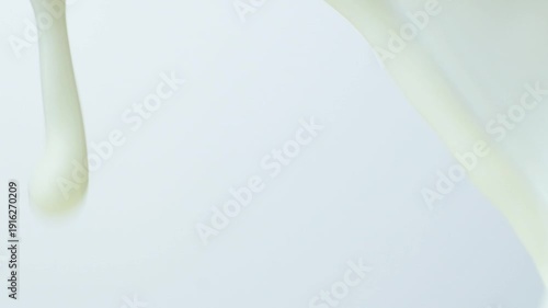 Macro texture of milk flowing in slow motion on white background, cooking milky background.
