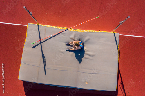 Germany, Baden-Wurttemberg, Winterbach, Female athlete sitting on mat after failed high jump