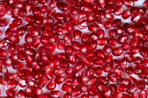 Gleaming pomegranate seeds used as garnish on porcelain, scattered composition, luxury dessert styling for pastry chef, appetizing red highlights, editorial food photography