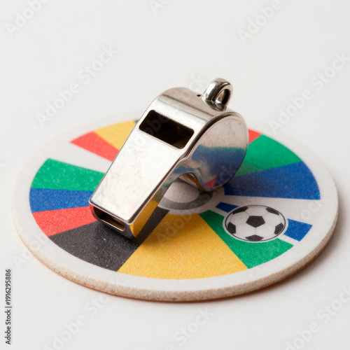 Metal whistle on round coaster with rainbow pattern symbolizing inclusivity authority and football fairness
