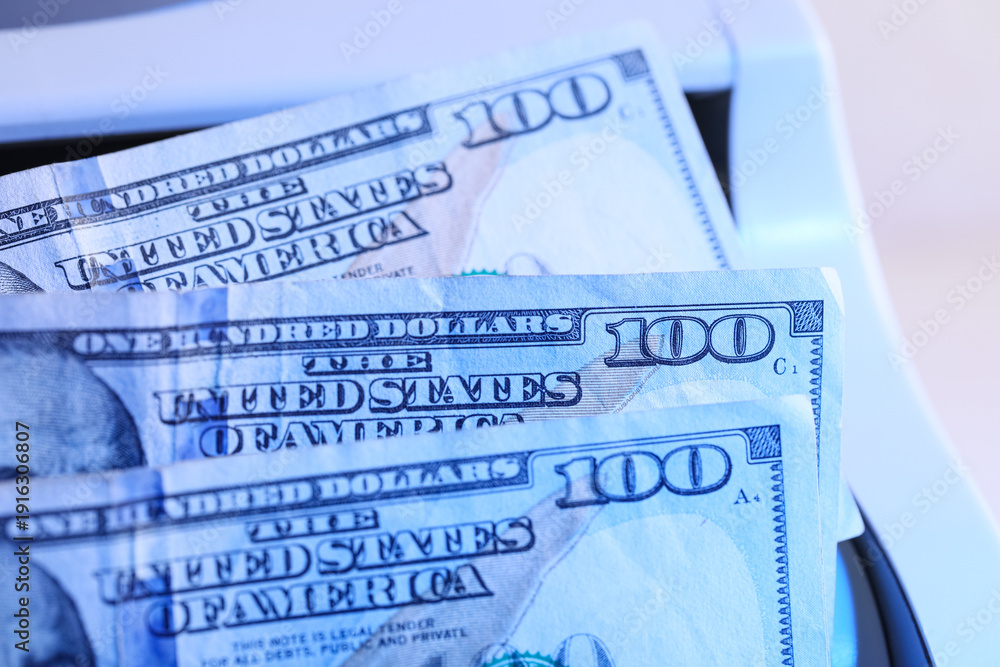 Naklejka premium Modern cash counting machine scanning ultraviolet with dollar banknotes on white background, closeup