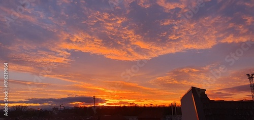 Phone photo of an orange and blue sunset with textured clouds. Dramatic evening sky showing color contrast, weather patterns, and calm outdoor atmosphere.
