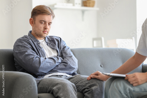 Female psychologist supporting man with suicidal thoughts on sofa in office