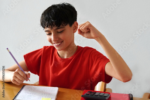 Фотография Teenage boy proudly celebrates solving a problem while doing his homework