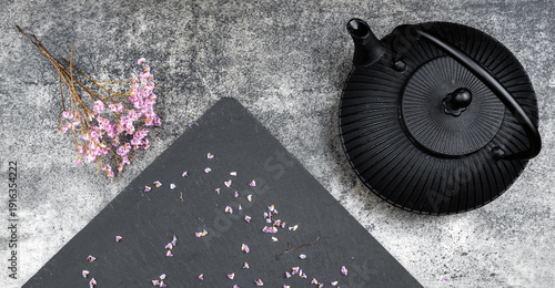 Black japanese teapot with cherry blossoms on stone background