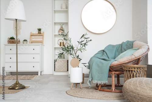 Interior of light living room with armchair and trash bin