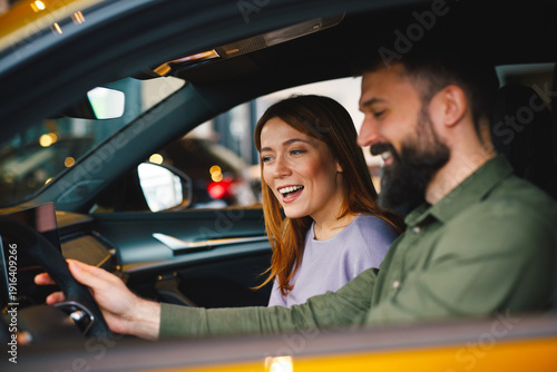 Excited couple exploring dashboard of their new car