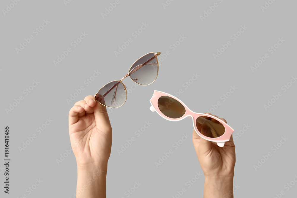 Fototapeta premium Female hands with different stylish sunglasses on grey background