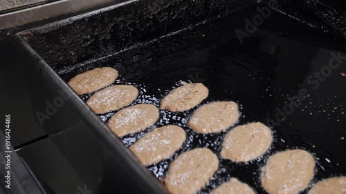 The cook puts the cutlet blanks in oil in a restaurant in an industrial kitchen. Close-up