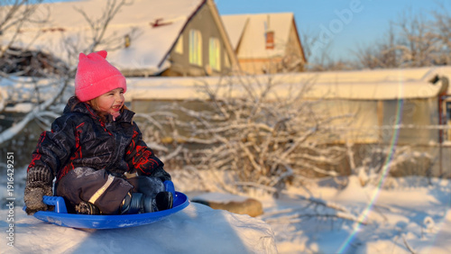 Εκτύπωση καμβά Young child experiencing joy and outdoor fun while actively sledging on fresh snow, wearing warm winter clothing, enjoying a sunny winter day with golden light