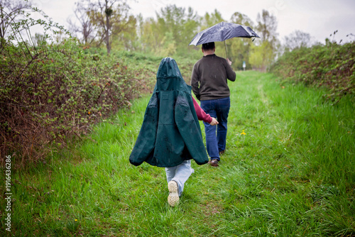 Wide-angle lifestyle scene of a father and daughter walking in gentle rain. A soft and close moment of offline escape, quiet support, and slow living without rush or extremes.