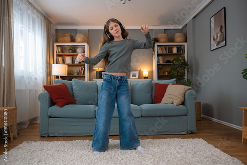Girl dancing happily wearing headphones in living room
