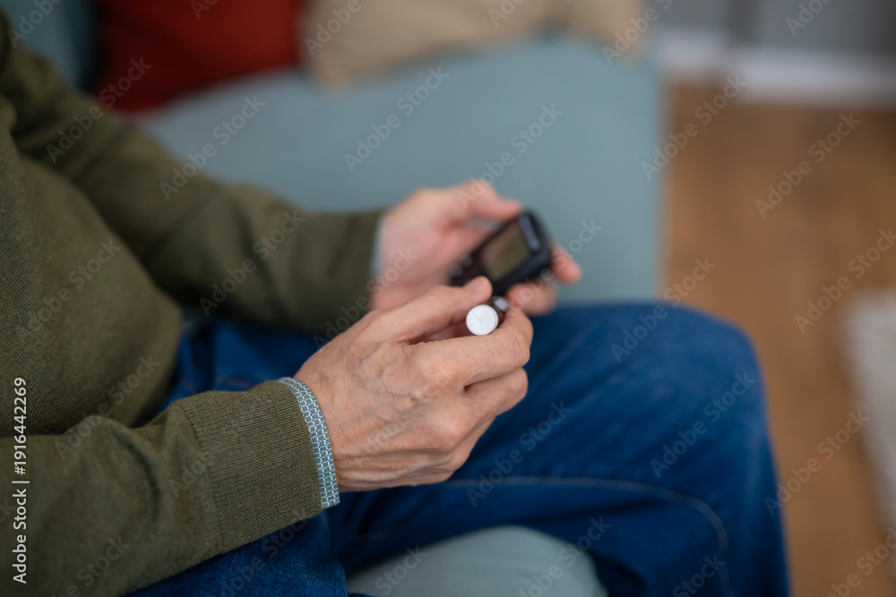 Obraz premium Senior man checking blood sugar with glucometer