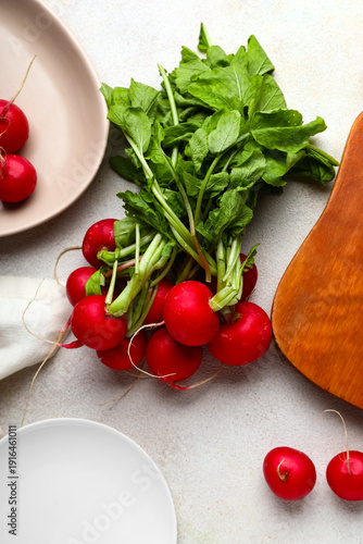 Board and plate of fresh radishes with leaves on white background