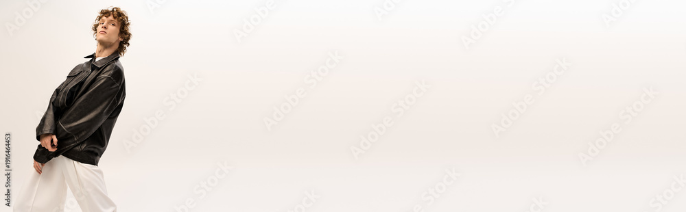 Fototapeta premium Stylish young man walks confidently in modern attire against a clean backdrop