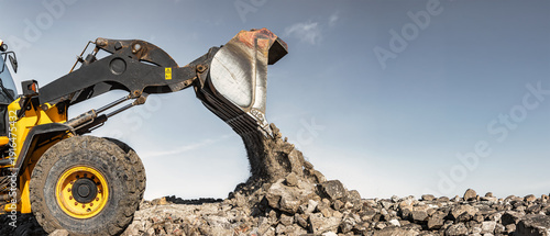 Foto Construction equipment, such as a loader or bulldozer, lifts rocks and dumps them onto a pile at a construction site