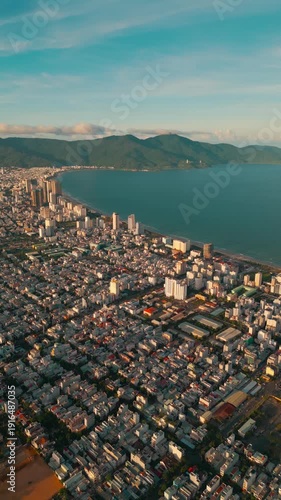 sunset in Vietnamese Da Nang city, My Khe sand beach and touristic My An and Son Tra district with skyscraper hotels and resorts, blue sea of Danang, Vietnam, aerial drone view 4k, vertical video