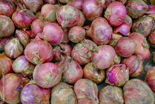 Close-up shot of a bountiful pile of vibrant red onions, organically grown and freshly harvested, showcasing textured skin and natural imperfections, perfect for culinary use and creating de