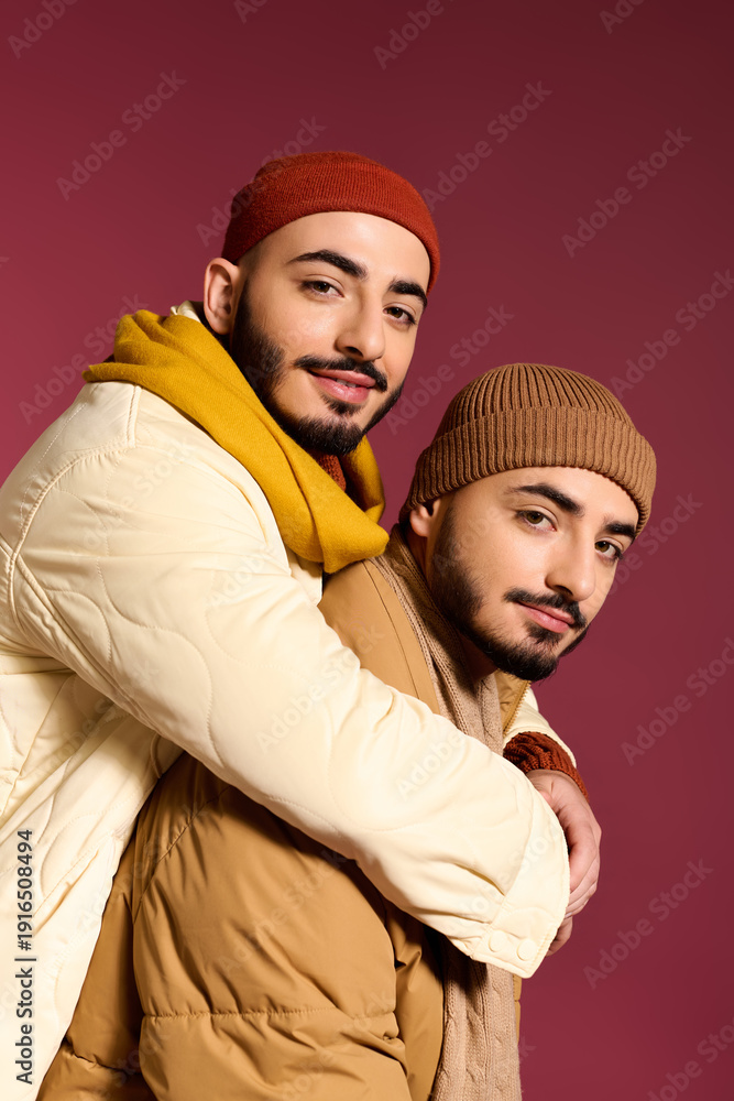 Obraz premium Stylish twins share a warm embrace in trendy winter fashion against a vibrant backdrop
