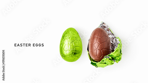 Two chocolate easter eggs, one wrapped in shiny green foil and one partially unwrapped, isolated on white background
