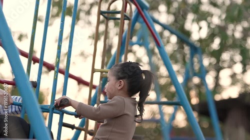 slow motion of cheerful child girl playing on double swing with her mother at outdoor playground