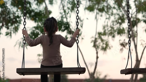 slow motion of cheerful child girl playing on a swing at playground