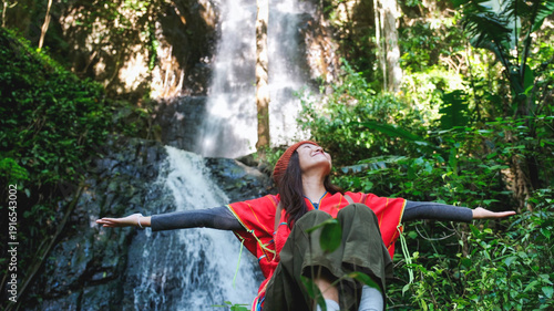 Obraz na plátně Portrait image of a woman with opened hands sitting in front of the waterfall in