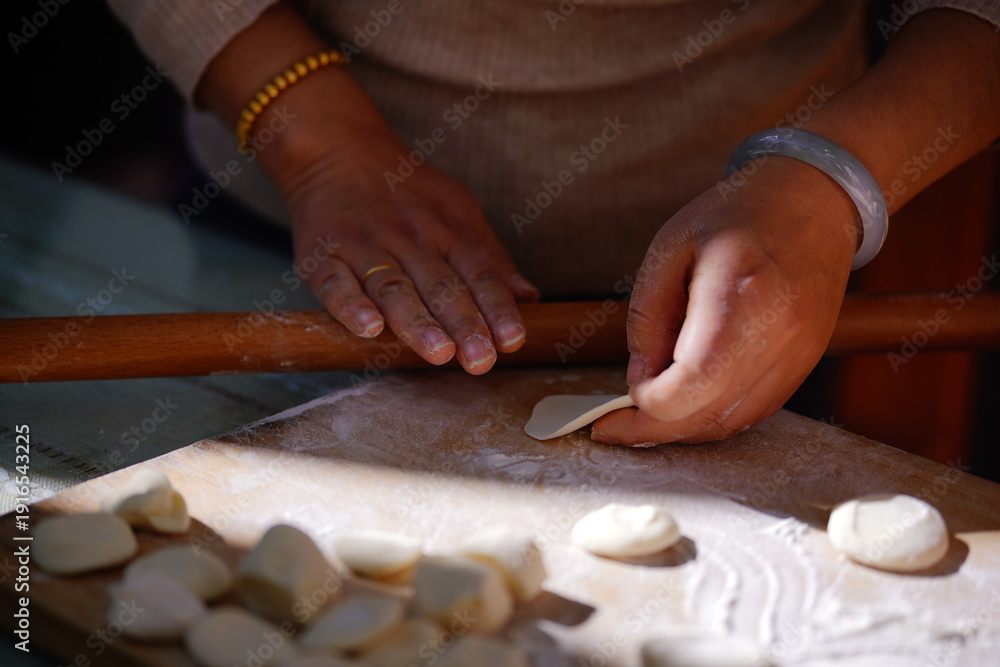 Obraz premium A focused close-up captures a woman's skilled hands shaping dumplings