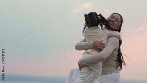 slow motion of Heartwarming moment of mother and child girl hugging at a sunset